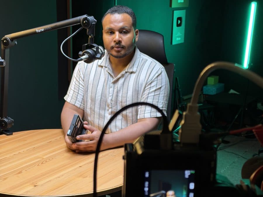 محمد سعيد في استوديو بودكاست، أمامه ميكروفون ومونيتور كاميرا